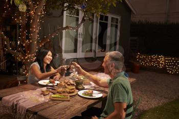 Mature Couple Enjoying Outdoor Meal In Backyard