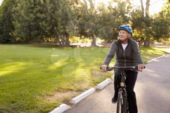 Front View Of Senior Woman Cycling Through Park
