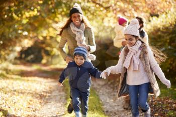 Family Running Along Path Through Autumn Countryside