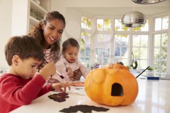 Mother And Children Making Halloween Decorations At Home