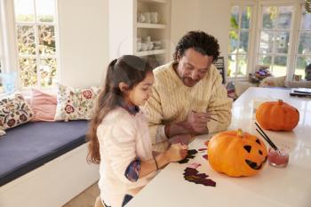 Father And Daughter Making Halloween Decorations At Home