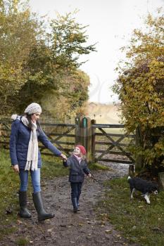 Mother And Daughter Taking Dog For Walk In Fall Landscape