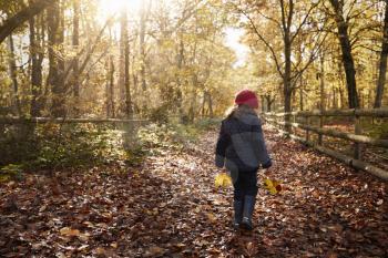 Young Girl Walking Along Path Through Autumn Countryside