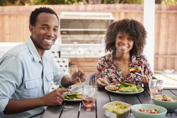 Young black couple eating in the garden looking to camera