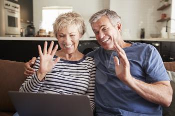Senior couple video calling on a laptop waving at screen