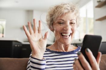 Senior woman video calling on smartphone at home, close up