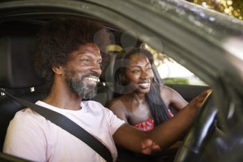 Two young black adults sitting in a car during road trip