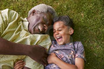 Laughing boy and granddad lying on grass, overhead close up