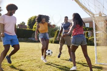 Two black adult couples playing football in garden