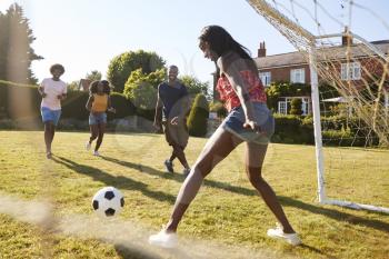 Black woman saving goal during a game of football in garden