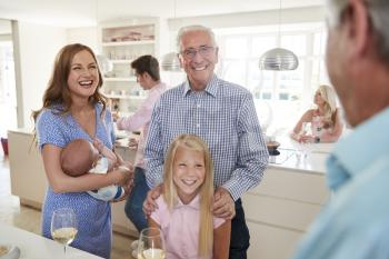 Multi-Generation Family And Friends Gathering In Kitchen For Celebration Party