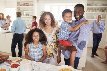 Portrait Of Family With Friends In Kitchen For Multi-Generation Party
