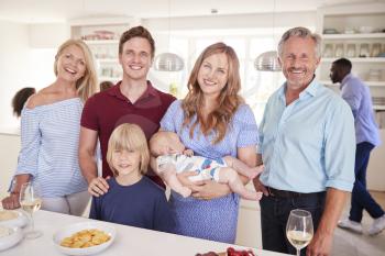 Portrait Of Multi-Generation Family And Friends Gathering In Kitchen For Celebration Party