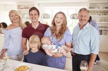 Portrait Of Multi-Generation Family And Friends Gathering In Kitchen For Celebration Party