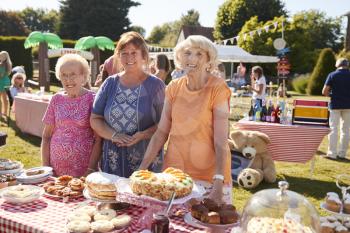 Portrait Of Women Serving On Cake Stall At Busy Summer Garden Fete