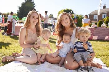 Portrait Of Two Mothers With Children On Rug At Summer Garden Fete