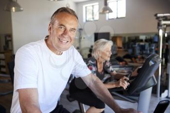 Portrait Of Active Senior Man Resting After Exercising On Cycling Machines In Gym