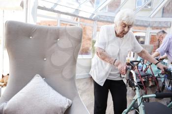 Senior Woman Using Mobility Aid In Lounge Of Retirement Home