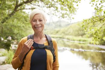 Portrait Of Senior Woman Hiking Along Path By River In UK Lake District