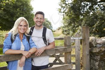 Portrait Of Couple Hiking In Lake District UK Looking Over Wooden Gate