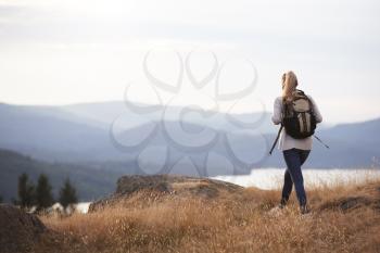 A young adult Caucasian woman hiking alone on a mountain peak, back view