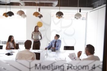 Businesswoman Giving Boardroom Presentation Viewed Through Meeting Room Window