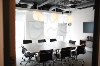 Chairs Around Boardroom Table In Empty Modern Meeting Room