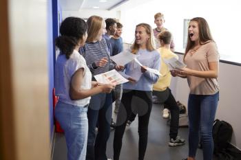 Excited Teenage High School Students Celebrating Exam Results In School Corridor
