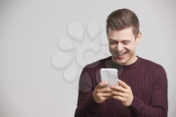 Portrait of a laughing young white man using a smartphone