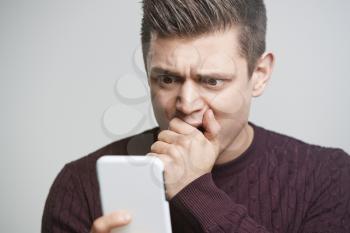 Cropped portrait of a shocked young man using a smartphone