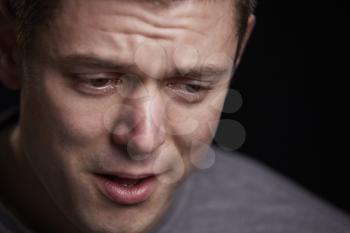 Close up portrait of crying young white man looking down
