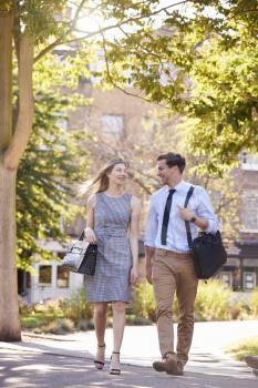 Businessman And Businesswoman Walk to Work Through City Park