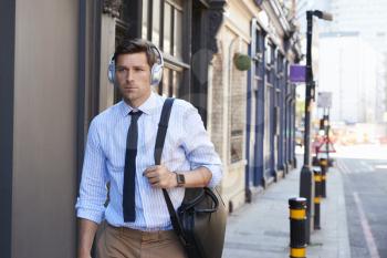 Businessman Wearing Wireless Headphones Walking To Work