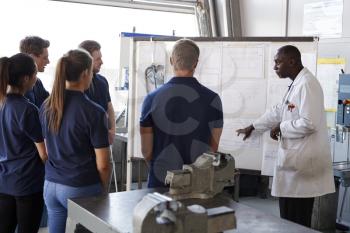 Engineer instructing apprentices at a whiteboard, close up