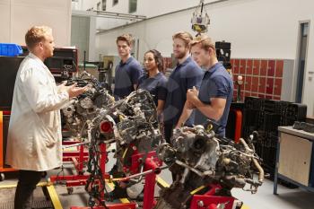Apprentices studying car engines with a mechanic