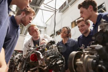 Mechanic showing engines to apprentices, low angle