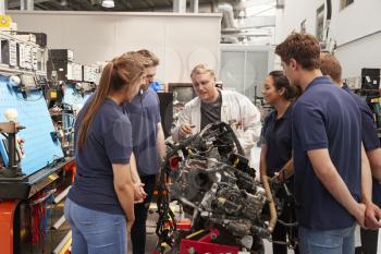Car mechanic showing engines to apprentices