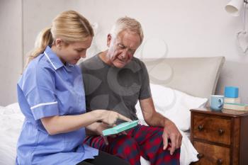 Nurse Helping Senior Man To Organize Medication On Home Visit