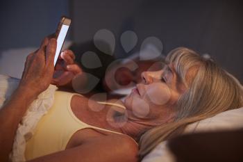Sleepless Senior Woman In Bed At Night Using Mobile Phone