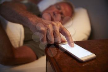 Sleepless Senior Man In Bed At Night Checking Mobile Phone