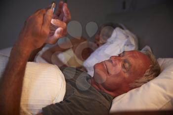 Sleepless Senior Man In Bed At Night Using Mobile Phone