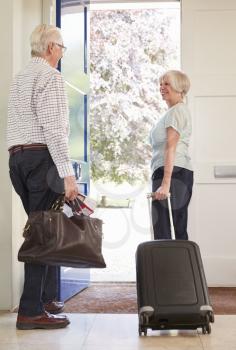 Senior couple with luggage leaving home for a holiday