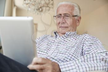 Senior man using a tablet computer at home, close up