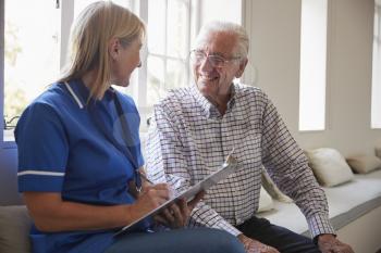 Senior man sits with nurse making notes at retirement home