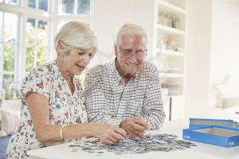 Senior couple doing a jigsaw puzzle at home