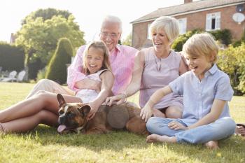 Grandparents and grandchildren sitting in garden with dog
