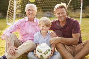 Three male generations of a family smile to camera outdoors
