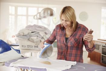 Distracted middle aged woman burns t shirt while ironing