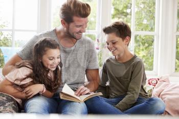 Father Reading Book With Son And Daughter At Home