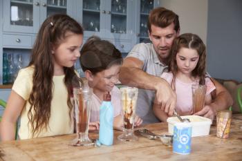 Father Making Ice Cream Sundaes With Children At Home